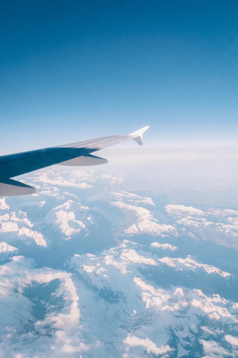 View from an aeroplane window of the wing over snow-capped mountains